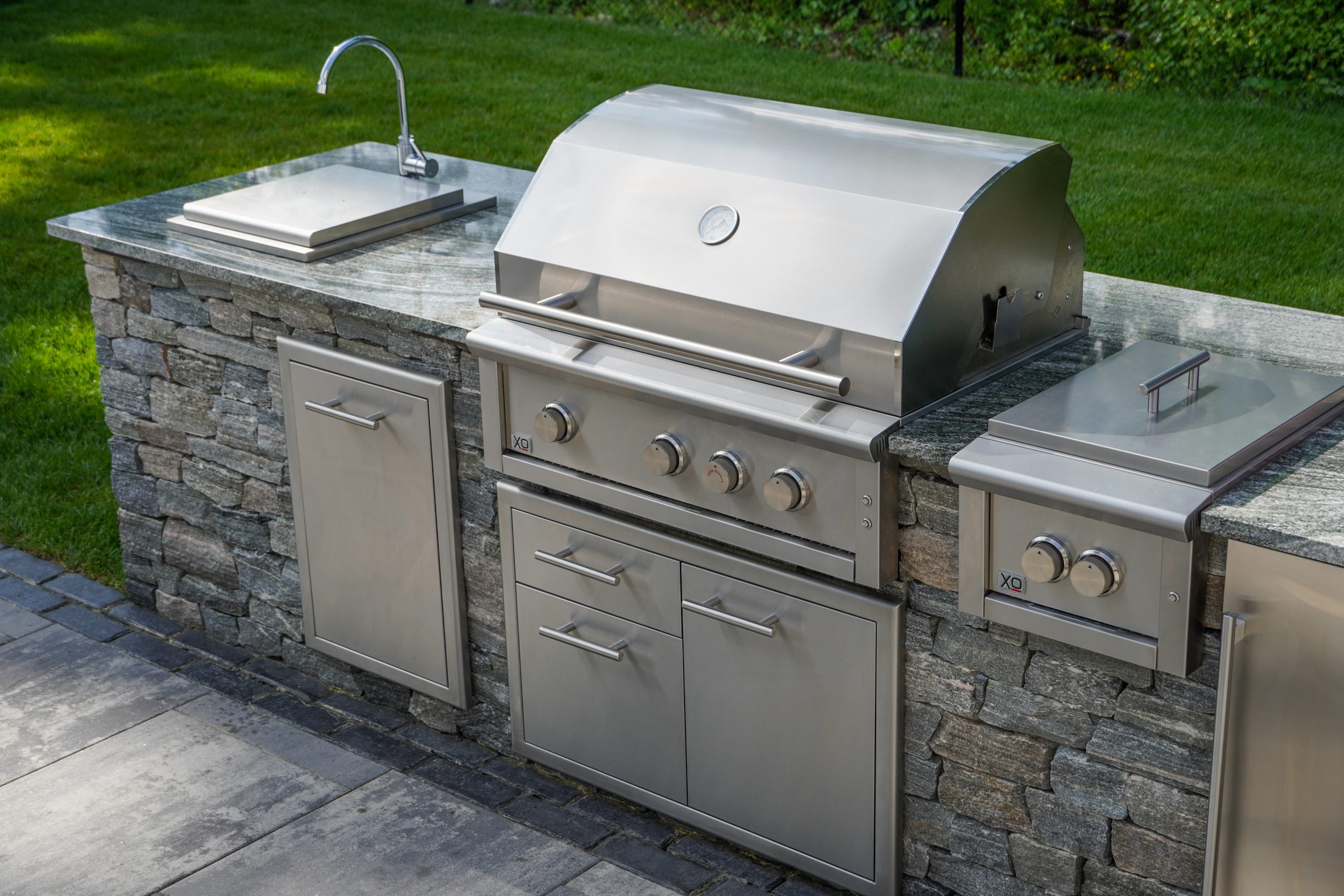 Built-in outdoor grill installation with stone veneer surround